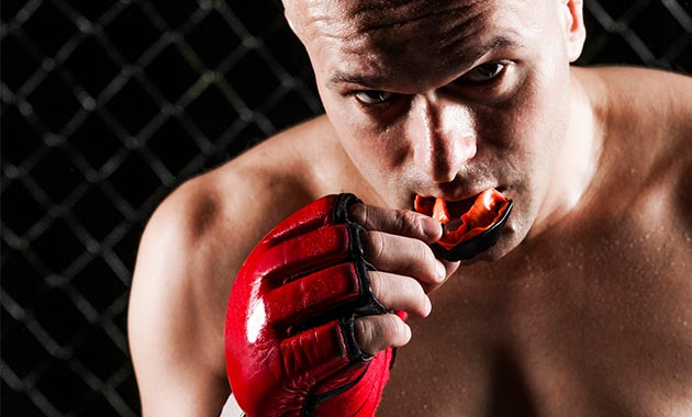 Combattant MMA insérant un protège dent rouge double mâchoire